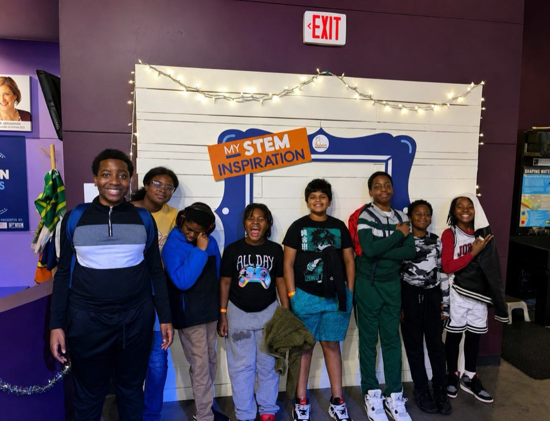 A group of campers posing in front of a STEM inspiration display