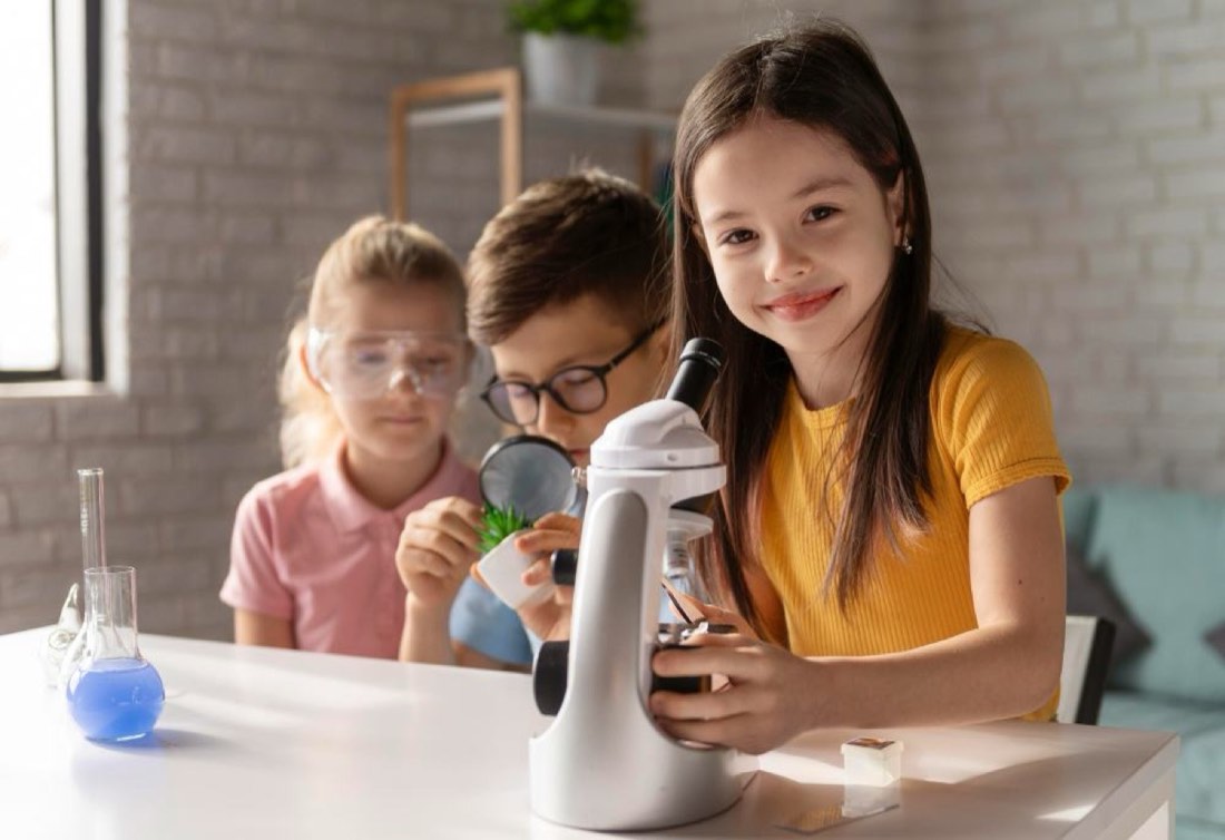 Three campers examining test tubes and a microscope during a science lab activity